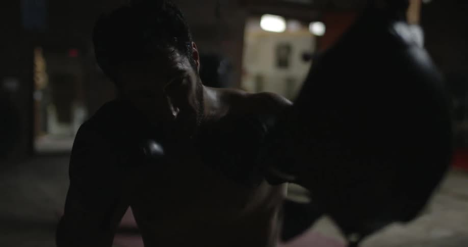 A man is in the gym punching a speed bag