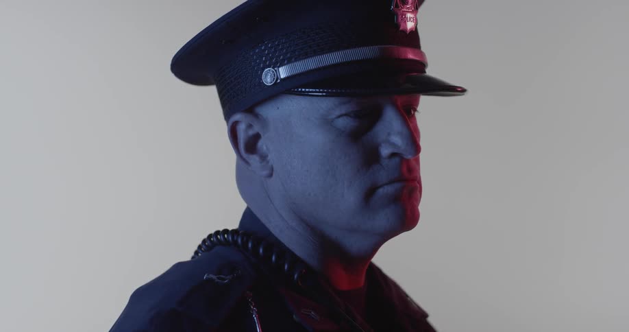 A man in a police uniform is turning to look straight ahead
