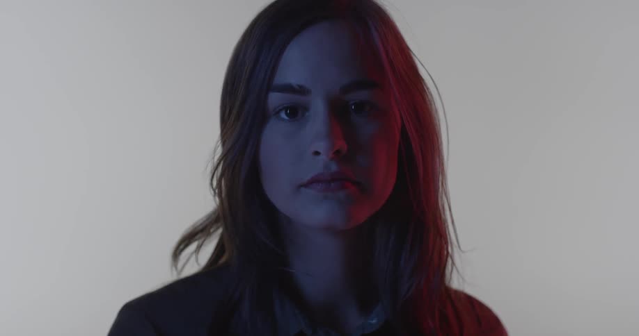 A woman is shifting her weight and blinking as she looks straight ahead
