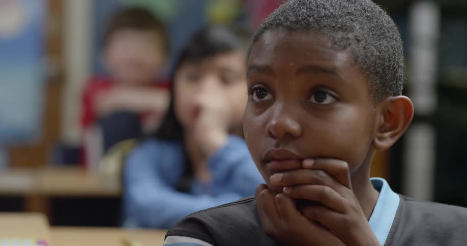 A boy is sitting in a classroom paying attention to a lesson during the day