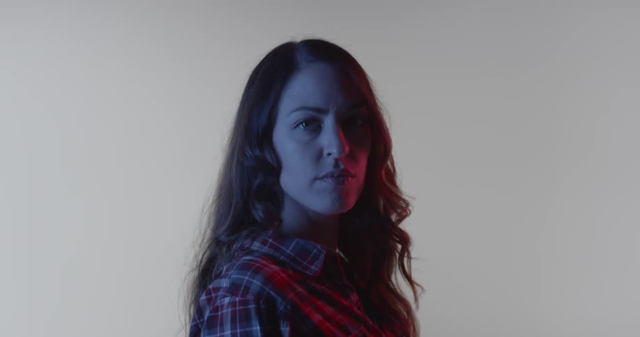 A woman turns around in a room with a white backdrop