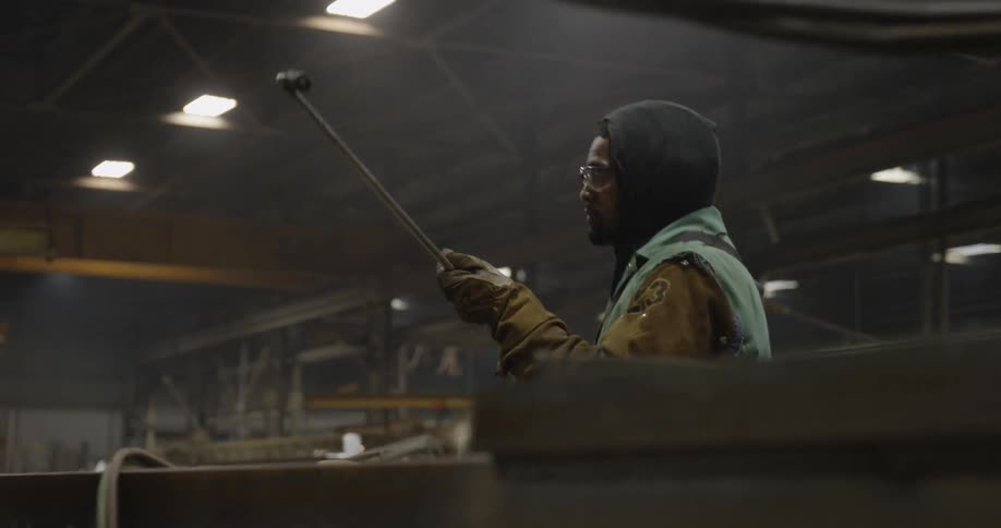 A man adjusts a long welding torch in a warehouse