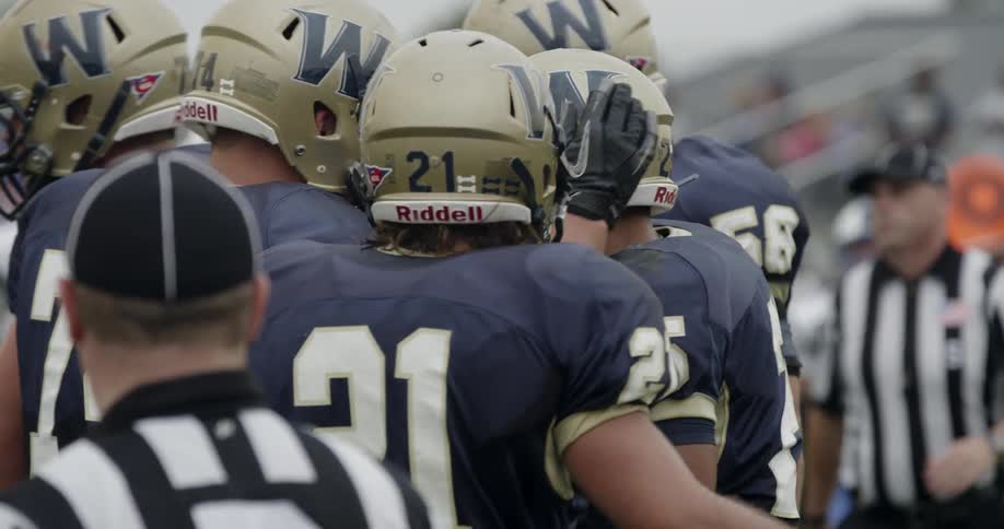 The football players all embrace hugging and tapping helmets