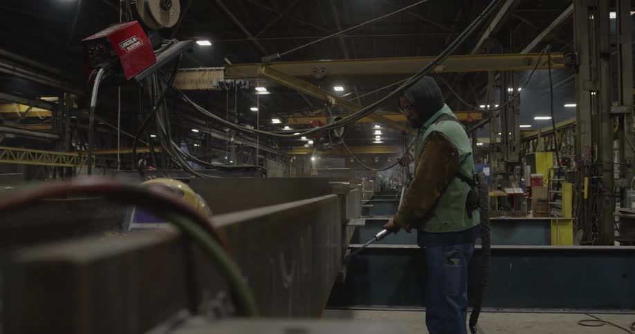 A man cleans a steel beam in a warehouse