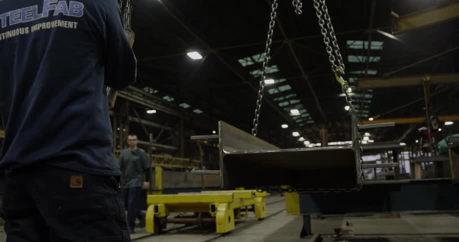 A steel beam is suspended by chains in a factory