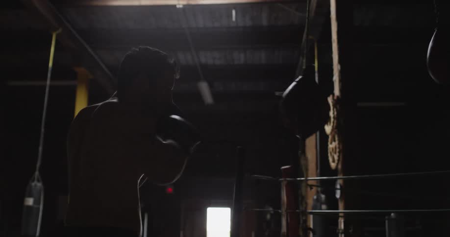 A man is punching a speed bag in a dark gym