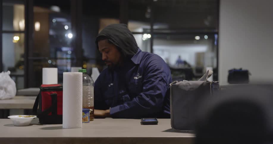 A man cleans up and stands from a lunch table at work