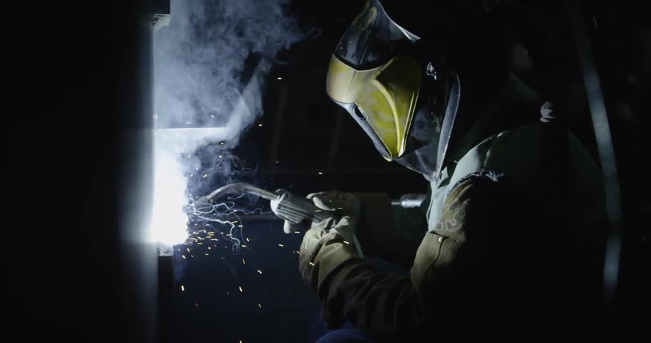 Man welding in a dark area