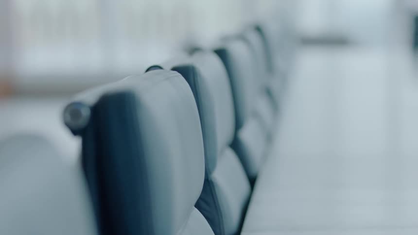 Empty chairs line a large table in an office building