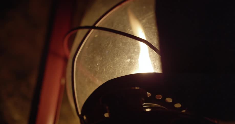 A flame is being lit in an oil lamp at night