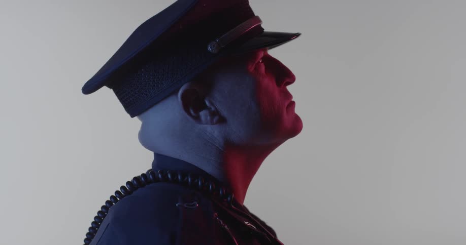 A police officer looks upwards while frowning
