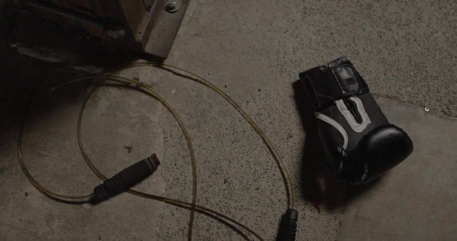 A boxing glove sits on a concrete floor