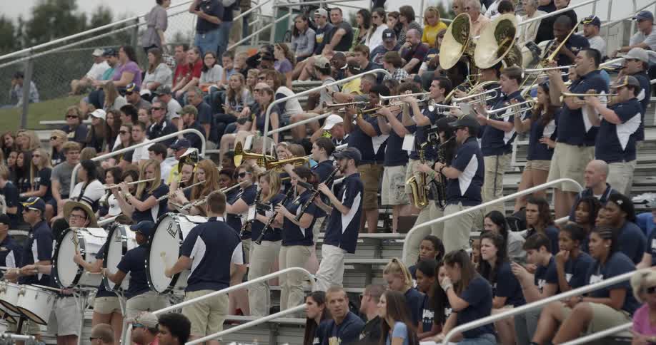 A band plays in bleachers at a football game
