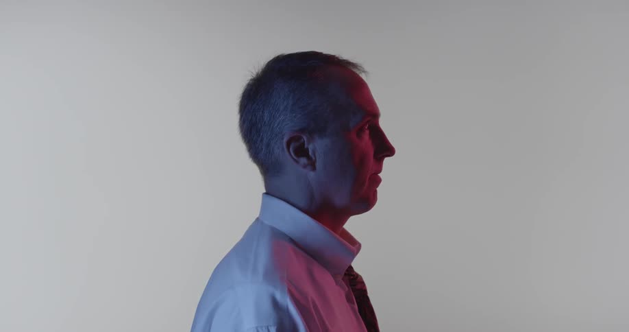 A man in a button-up shirt and tie looks upwards