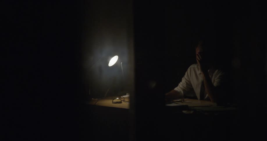 A man gets frustrated and rubs his eyes while working at a desk