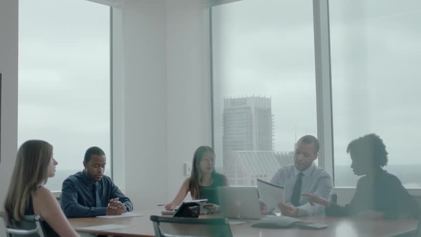A group of people are working at a conference table in an office during the day