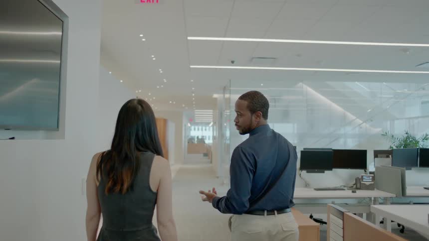 Man and woman walk through office and talk