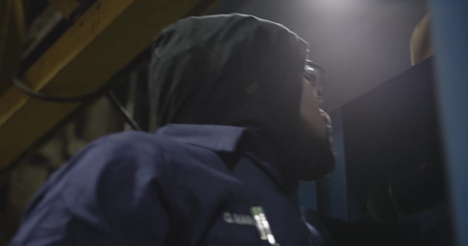 A man is putting on eye protection in a factory