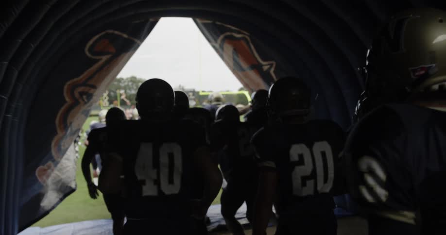A football team is walking out of the tunnel from the locker room and onto the field