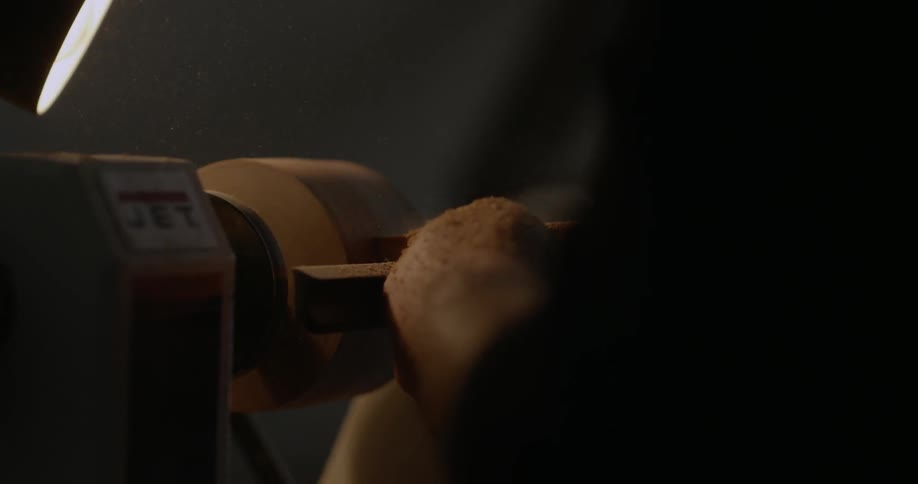 A man sands a piece of wood in a workshop
