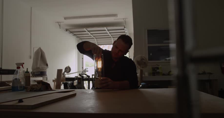 A man screws a light bulb into a lamp base