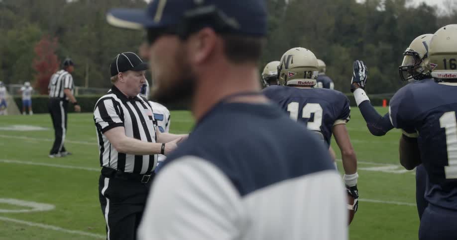 Football player walks and throws the ball back to other players