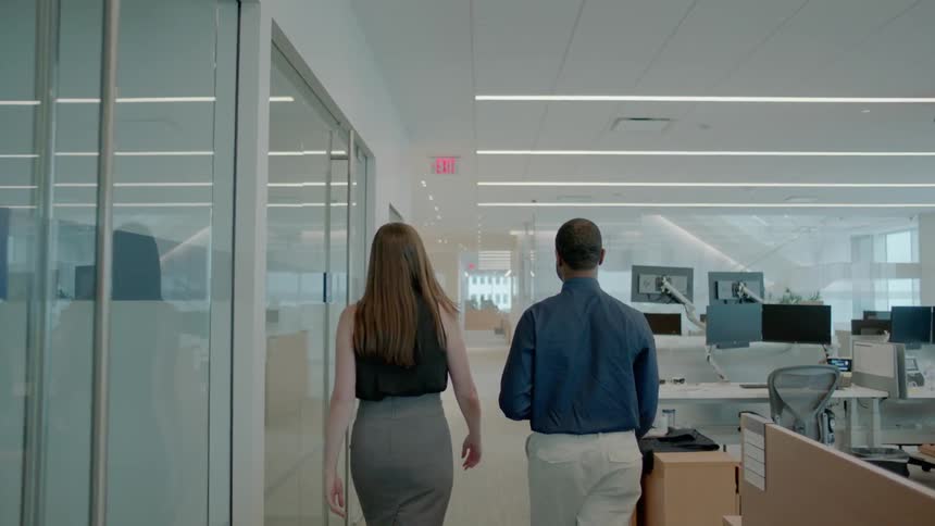 Man and woman walk through office and talk