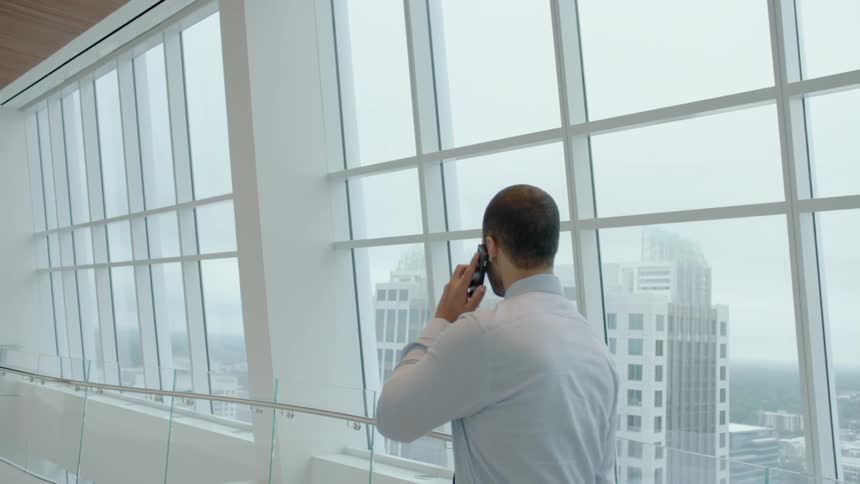 A man walks in an office building while using his phone