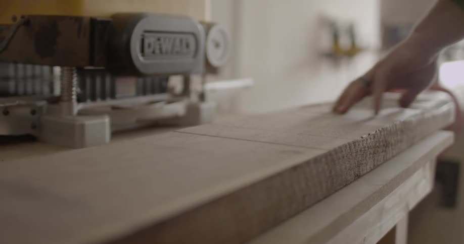 A man puts a piece of wood down by a table saw