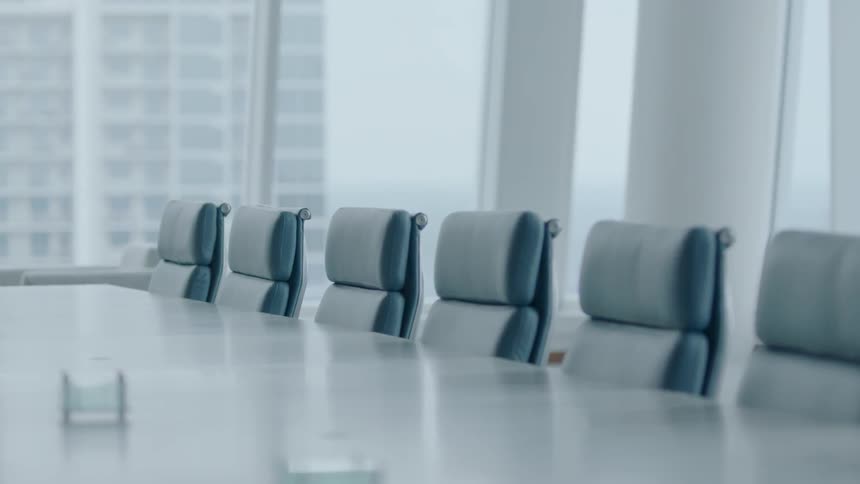 An empty conference room with large windows overlooks other city buildings