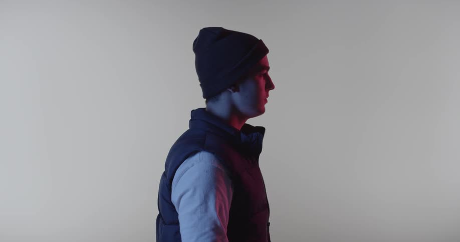A man with a puffer vest and beanie stands still