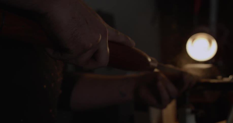 A man shaves a piece of wood on a lathe