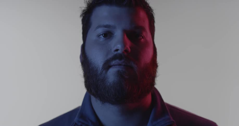 A bearded man is staring in the dark room