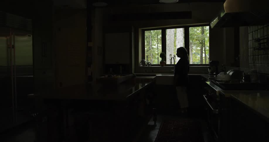 A woman stands at a kitchen sink