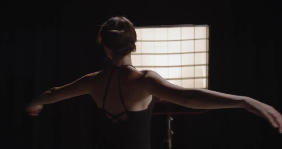 A ballerina dances in a dark room