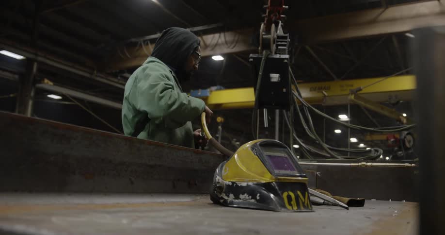 A man is working with welding equipment in a factory