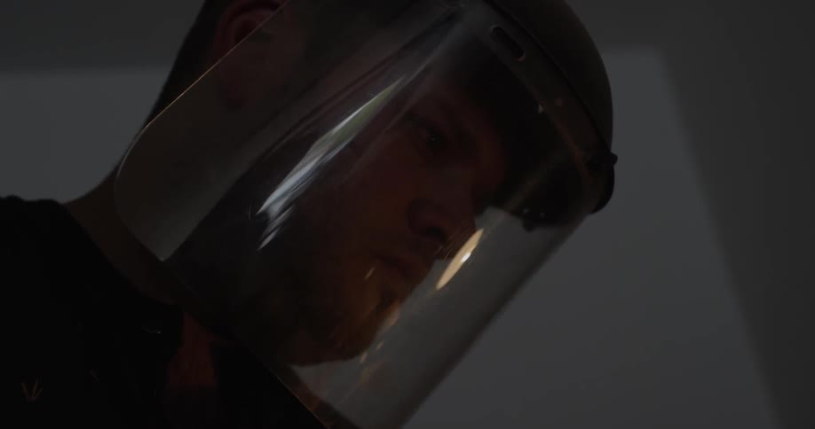Man wearing a helmet with a clear shield looks down