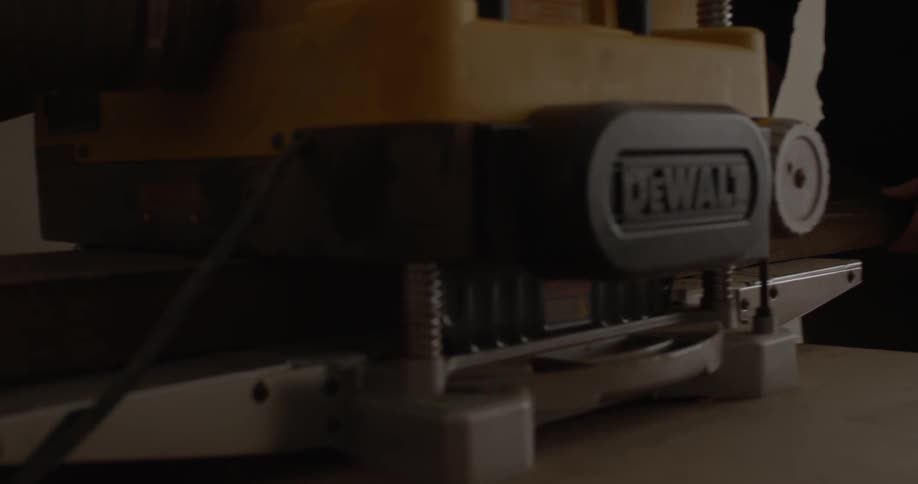 A man is putting a wood board through a drum sander