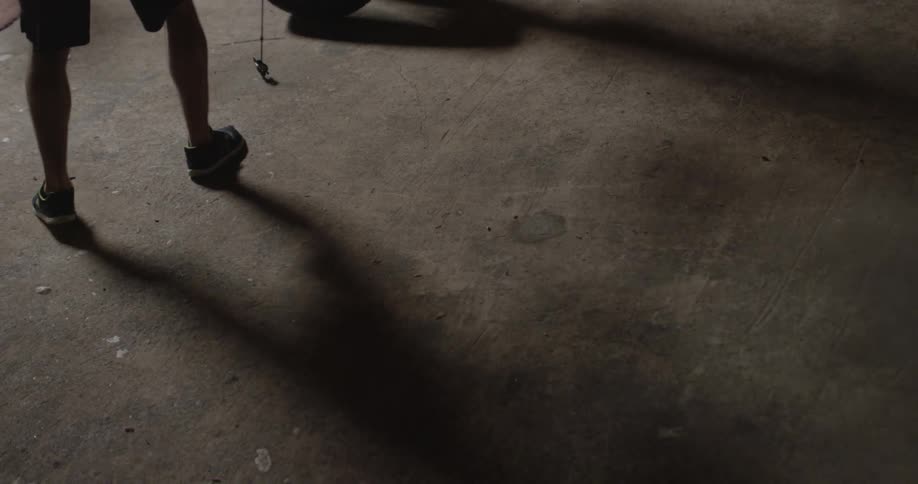A boxer is punching a bag in a gym during the day