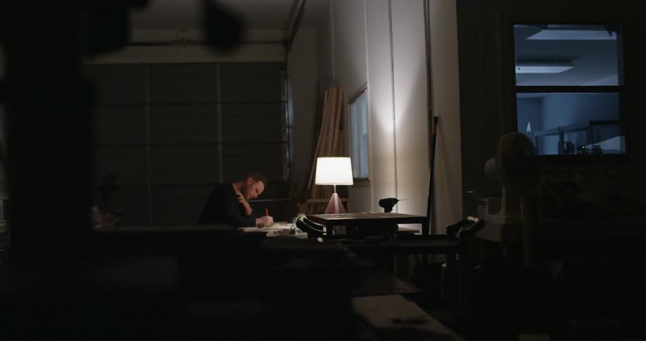 A man sits at a desk in a garage