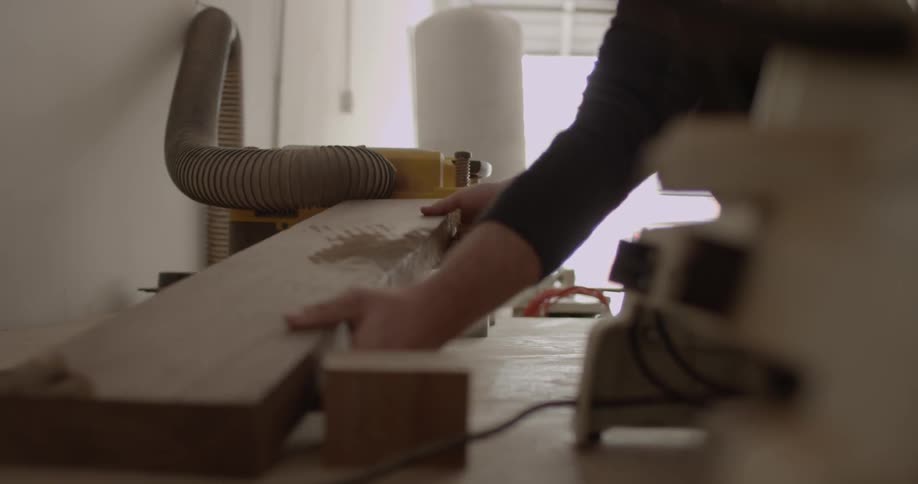 A man runs wood through machinery in a garage