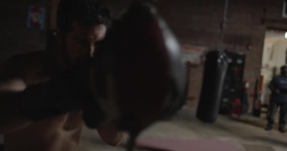 A boxer hits a punching bag in a gym