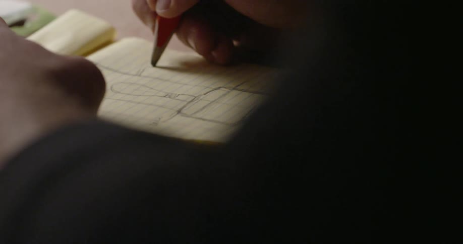 A person is drawing in a notebook with a pencil