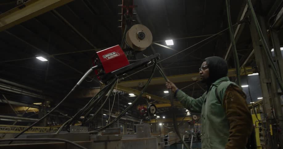 A man pools welding gear on a track in a warehouse