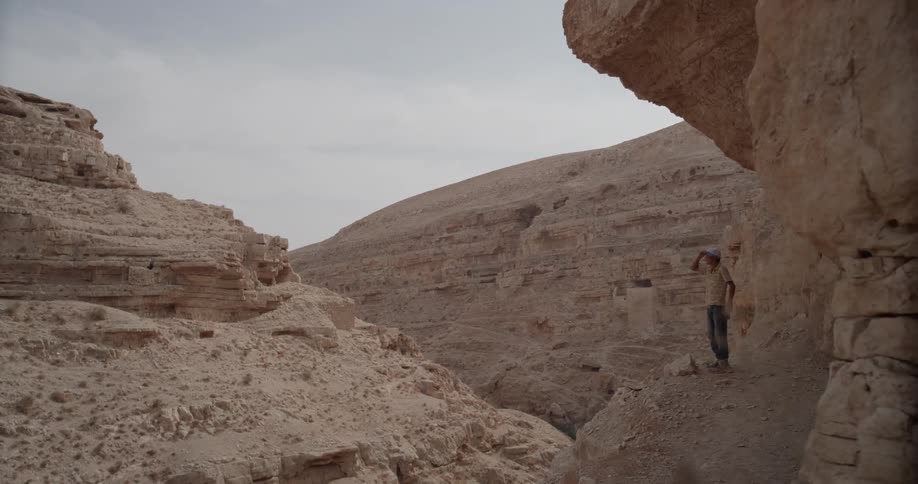 A man stands on a ledge inside a canyon