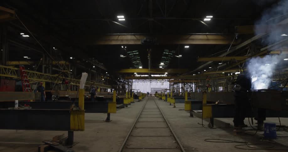 Person welding in a large industrious area