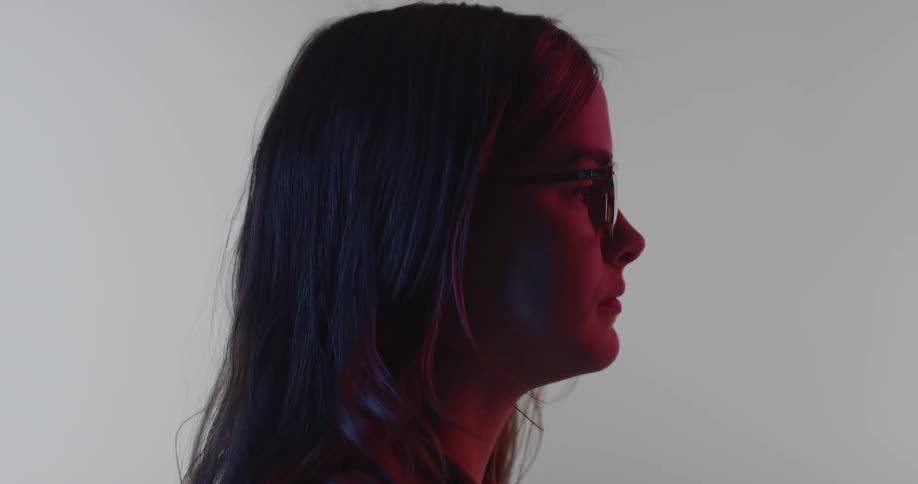 A girl wearing glasses is looking forward in the dark
