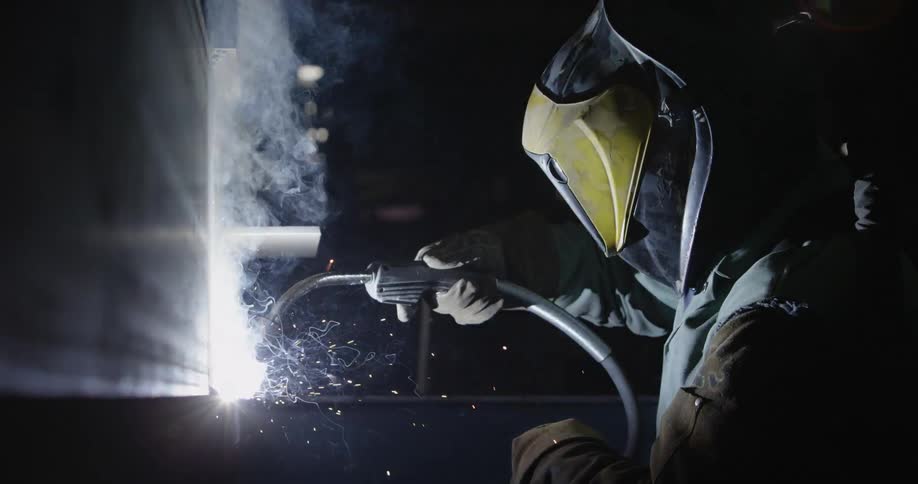 Sparks and smoke fly around a welder