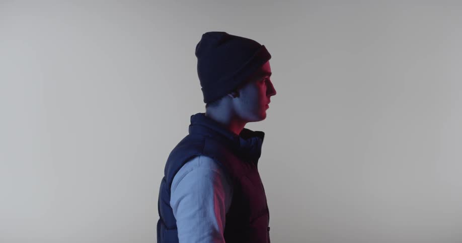 A man stares forward inside a room with a white backdrop