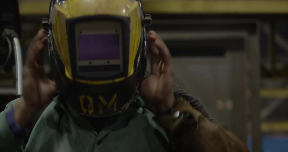 A worker attaches a welding mask to his head